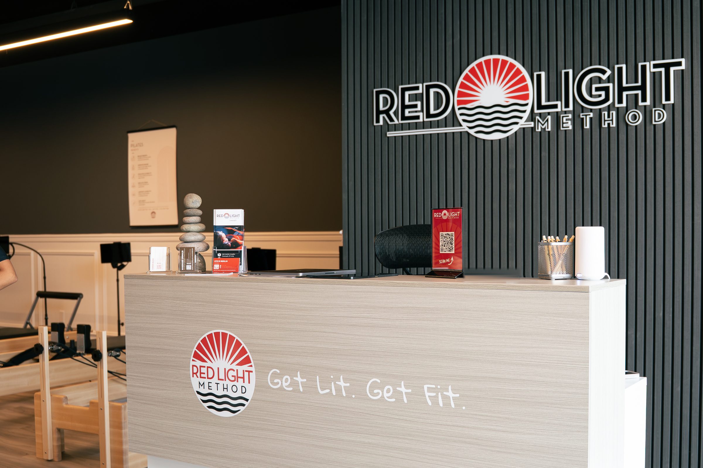 The welcome desk at Red Light Method Commack, with the studio wordmark on the slatted wall behind it.