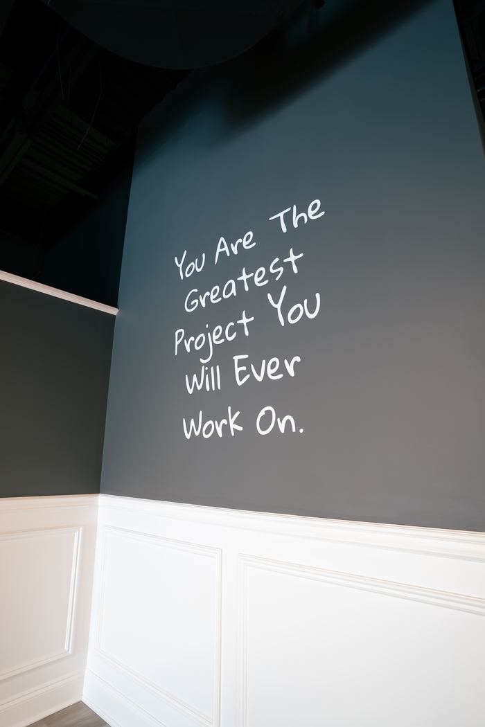 A studio wall hand lettered with the words You Are The Greatest Project You Will Ever Work On.