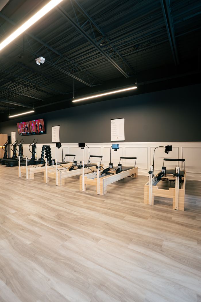 The Pilates reformer studio, empty and ready, with screens above each machine.