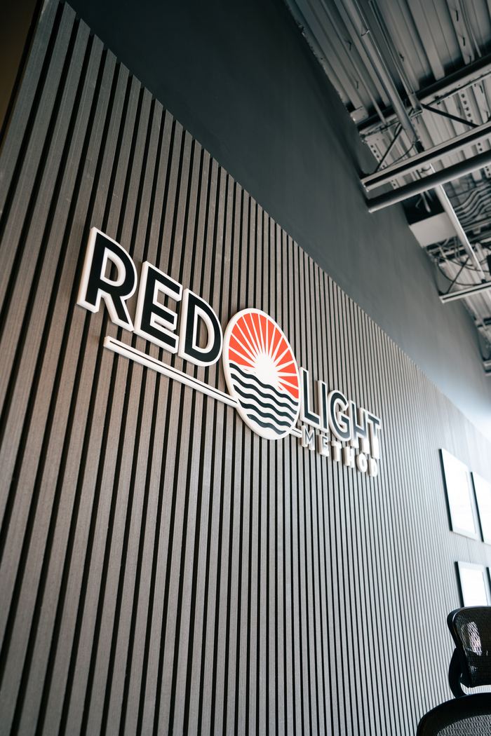The Red Light Method wordmark mounted on the black slatted wall.