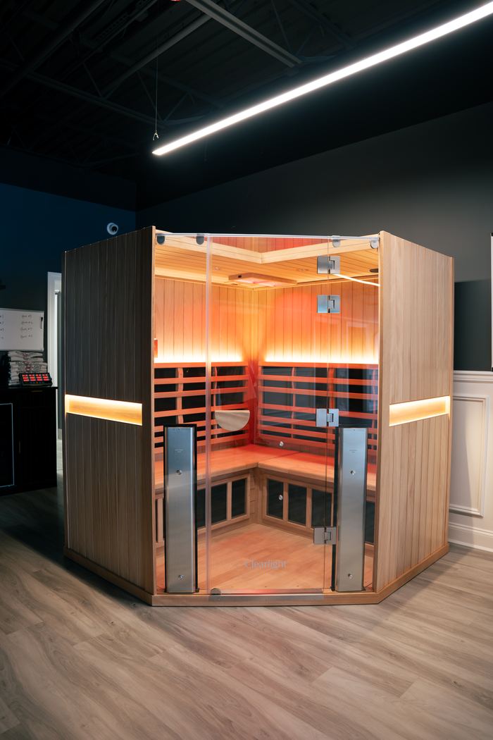 The far infrared sauna cabin, glass door open, glowing in the studio.