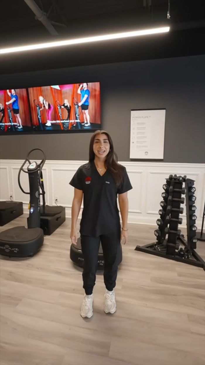 A team member standing beside the Power Plate platforms in the studio.