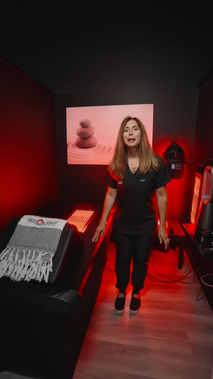 A team member in the red light therapy room, beside the treatment bed.